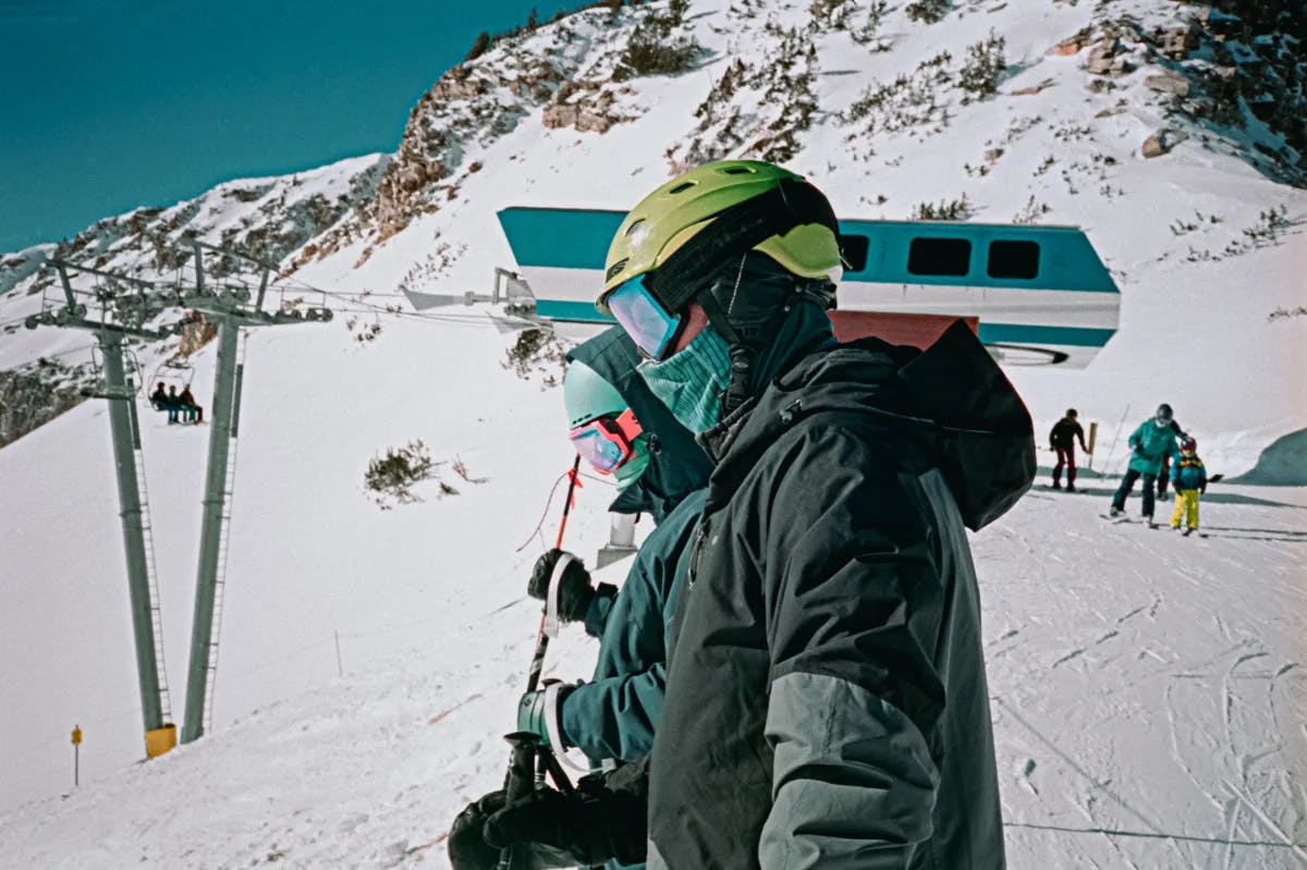 A picture of a man in black jacket and green helmet on snow covered mountain during daytime.