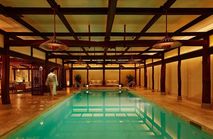 an indoor pool beneath a ceiling covered with wooden beams