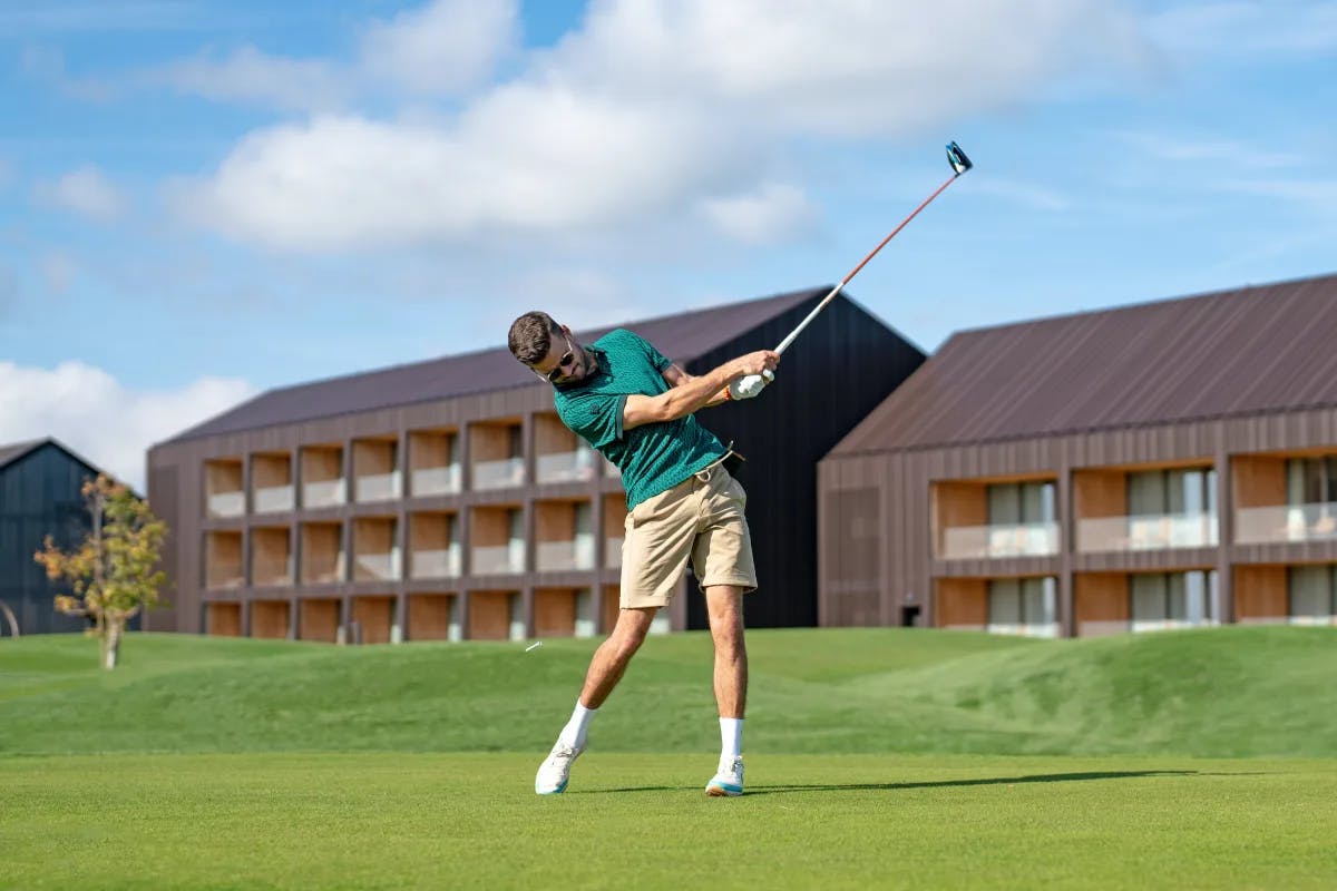 A picture of a man swinging golf club on a golf course.