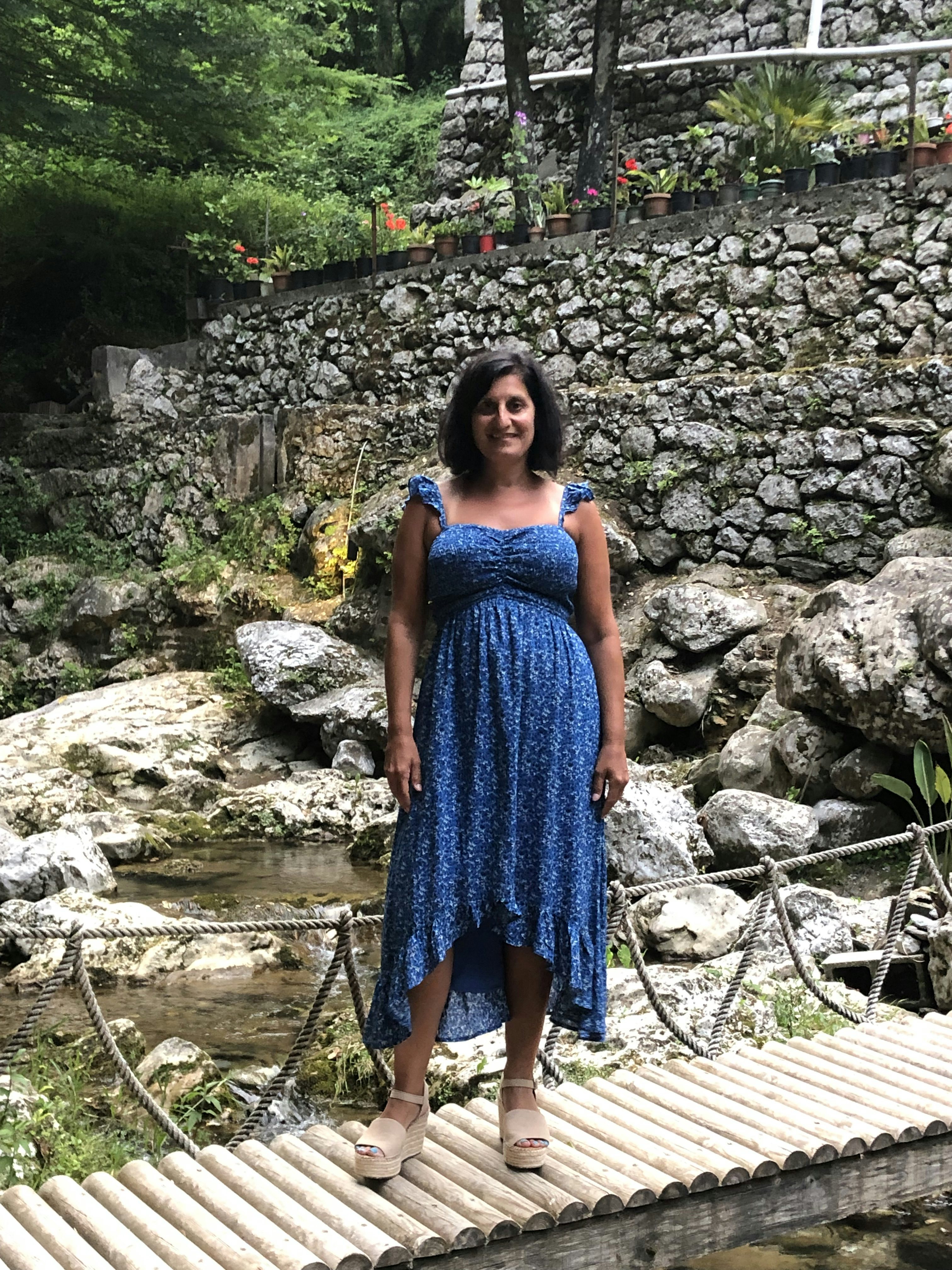Travel Advisor Lisa Kleingarn wears a blue dress standing on small foot bridge
