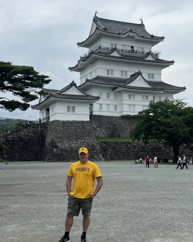 Michael wearing a yellow shirt and posing in front of a temple. 