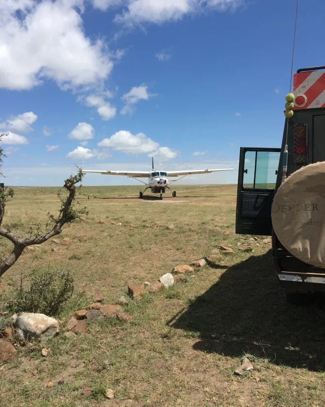 An airplane landing in a safari with a truck to the right of it