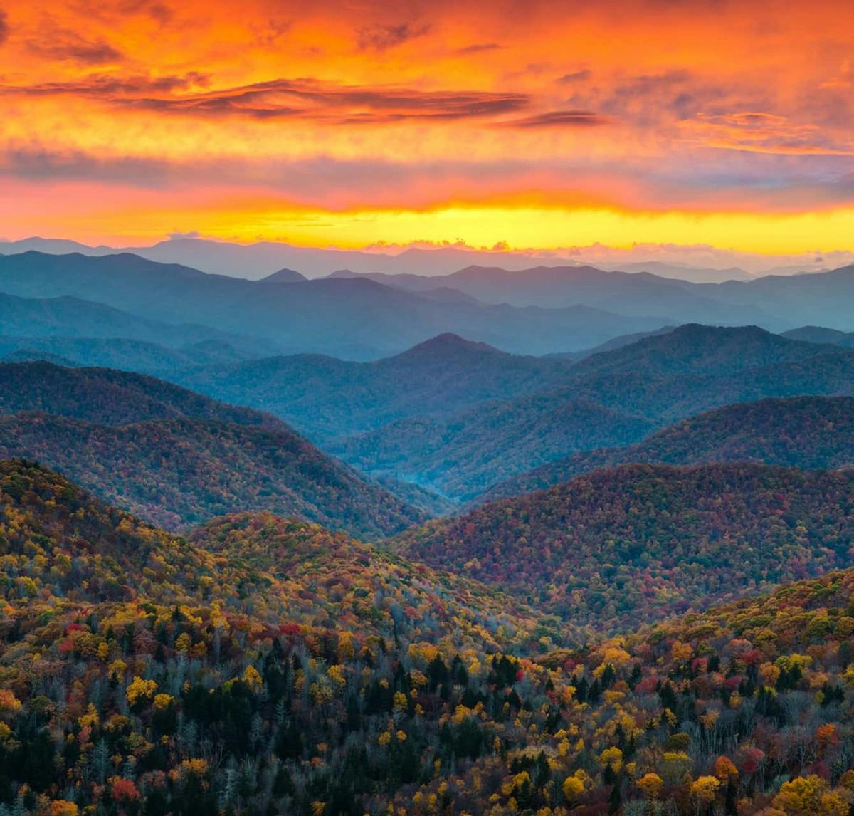 A view of the mountains during sunset with bright orange and yellow sky