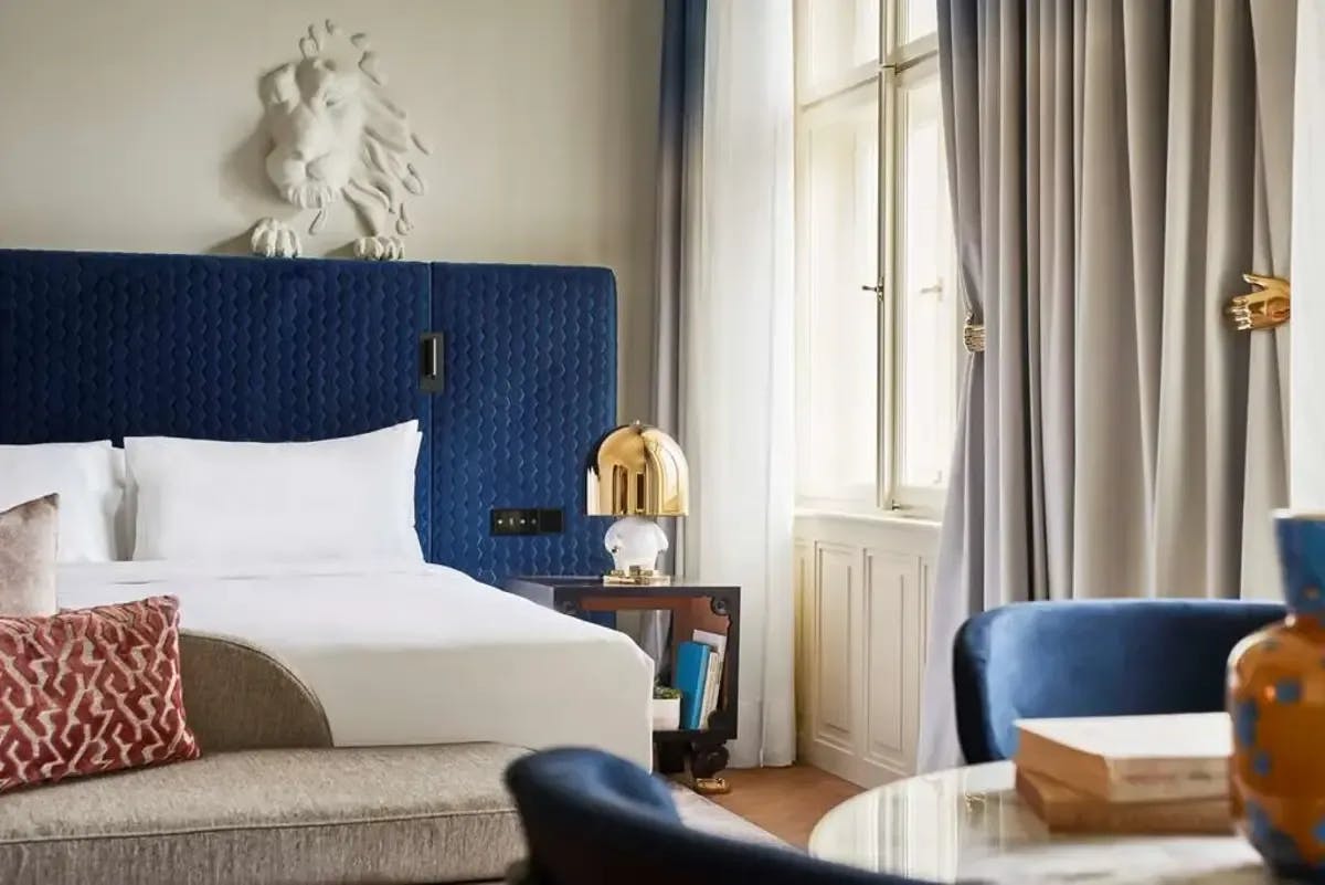 a close-up shot of a luxe hotel bedroom with blue curtains and blue bed backsplash