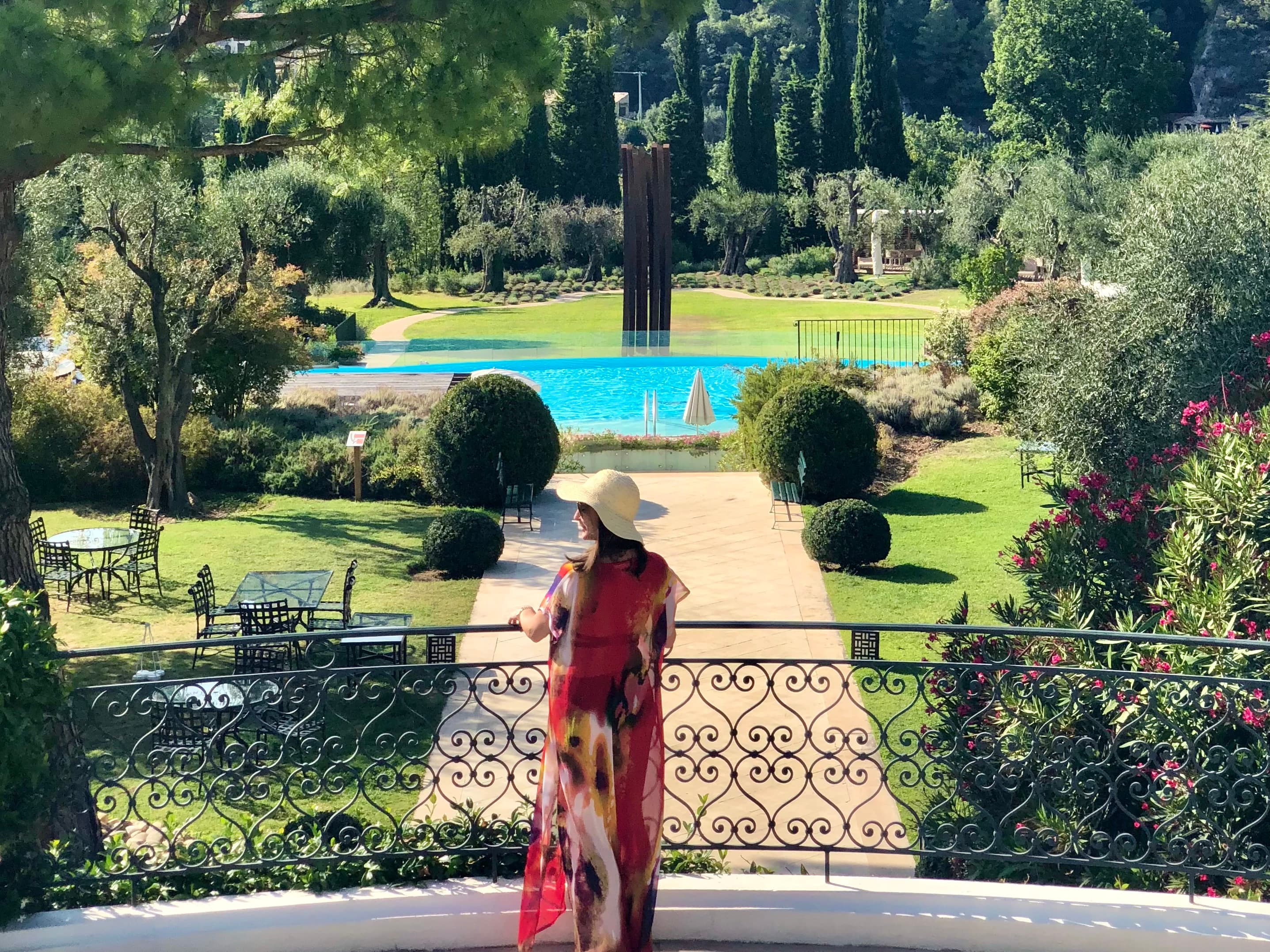 Picture of Arianna looking over a metal railing to a lovely park with a beautiful pond in the distance.