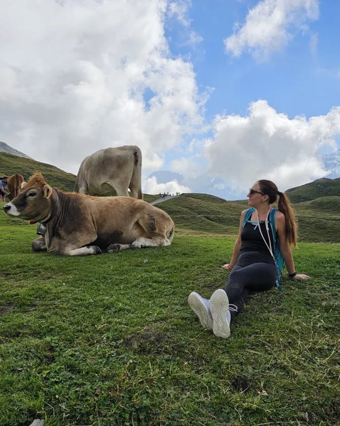 Picture of Alexandria sitting on grass with two cows next to her