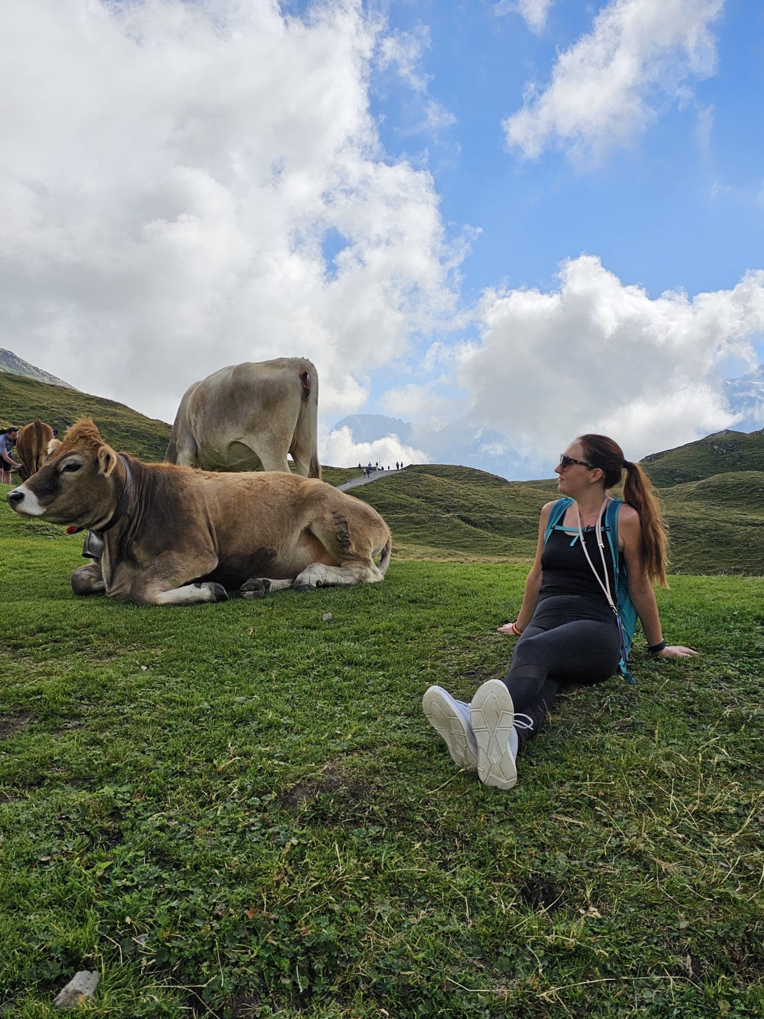 Picture of Alexandria sitting on grass with two cows next to her