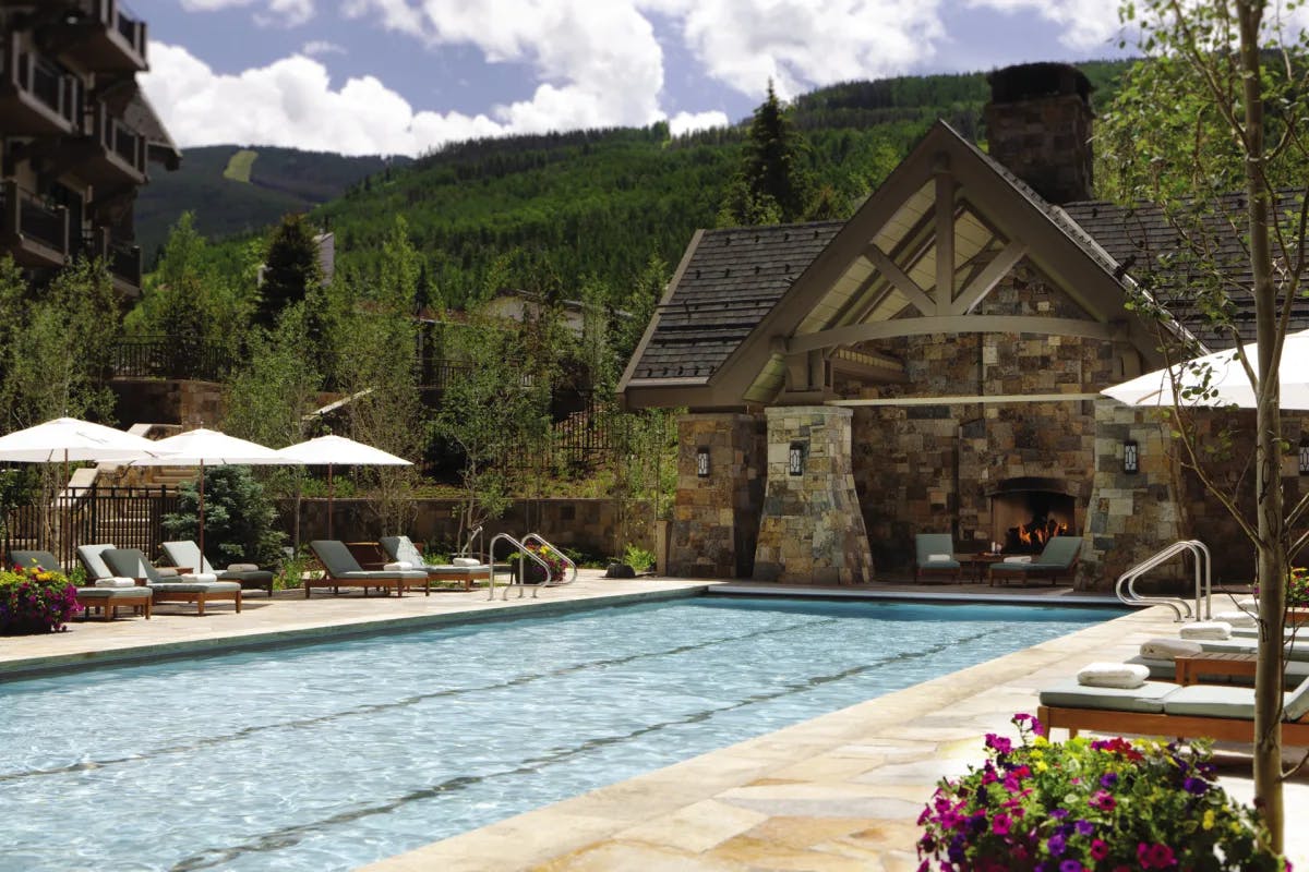 an outdoor pool in front a stone-and-wood alpine building