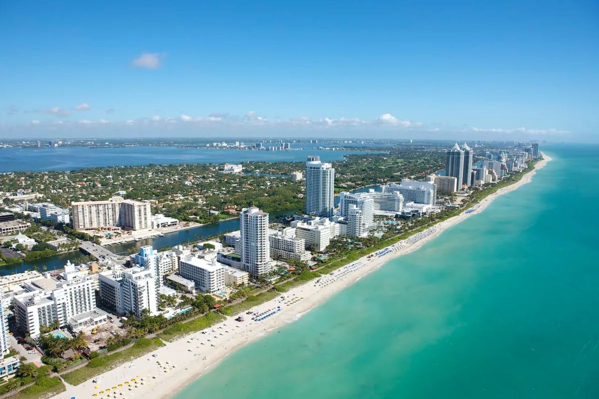 The long island of Miami Beach, with urban high-rises lining white shores and sapphire water on either side