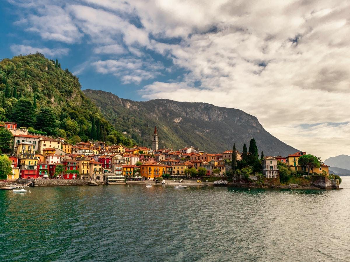 Sea side Italian town, Lake Como in front of mountains on a cloudy but sunny day.