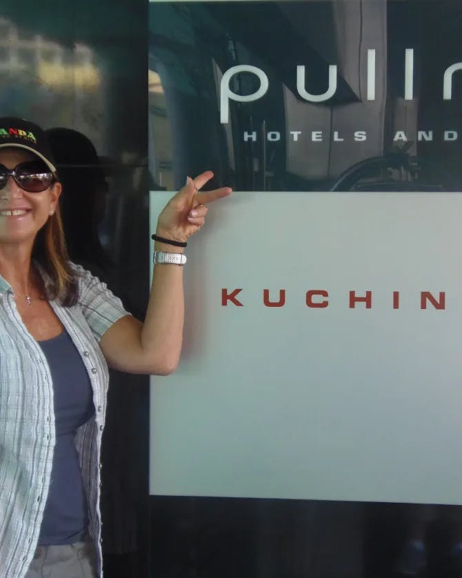 Picture of Jane Herman wearing black hat and sunglasses outside a hotel
