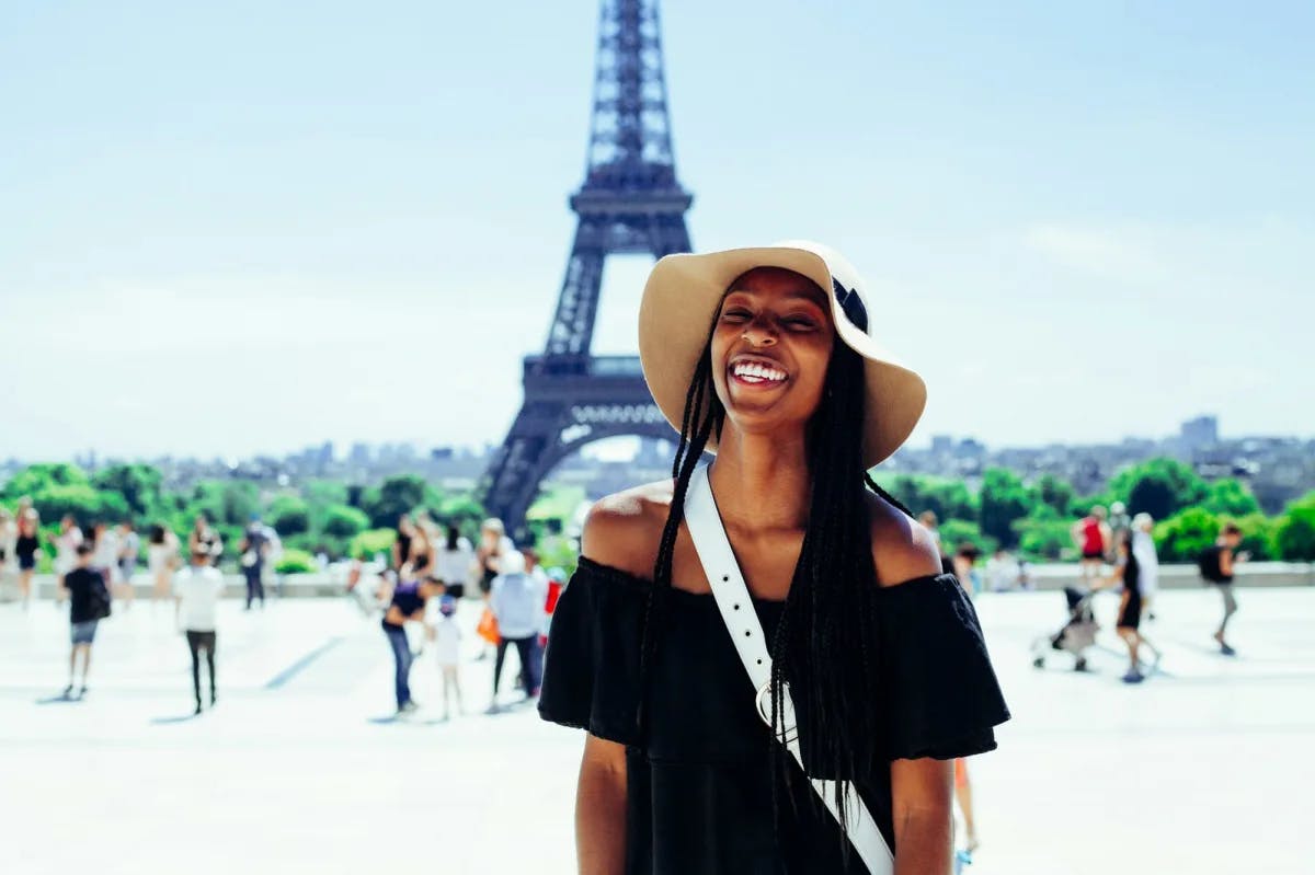 A young woman smiles ecstatically with the Eiffel Tower in the background 