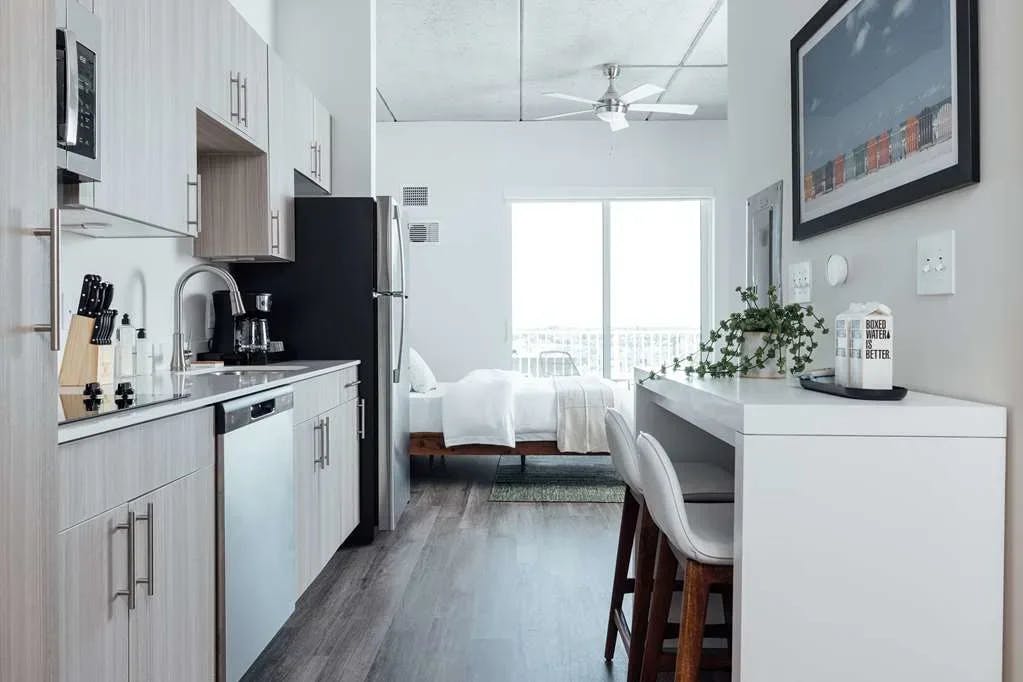 a modern apartment with a kitchen and a white bed