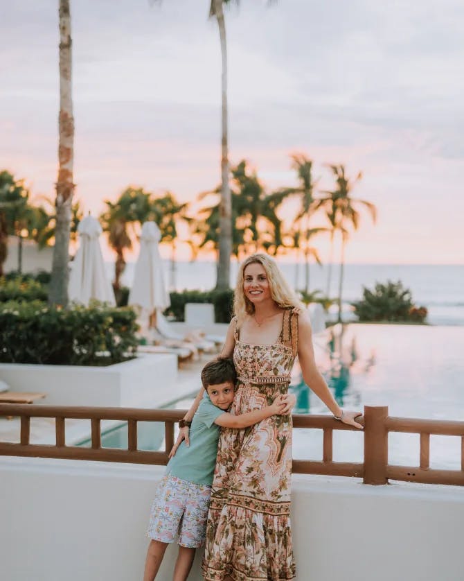 emily with kid and an ocean view with palm trees