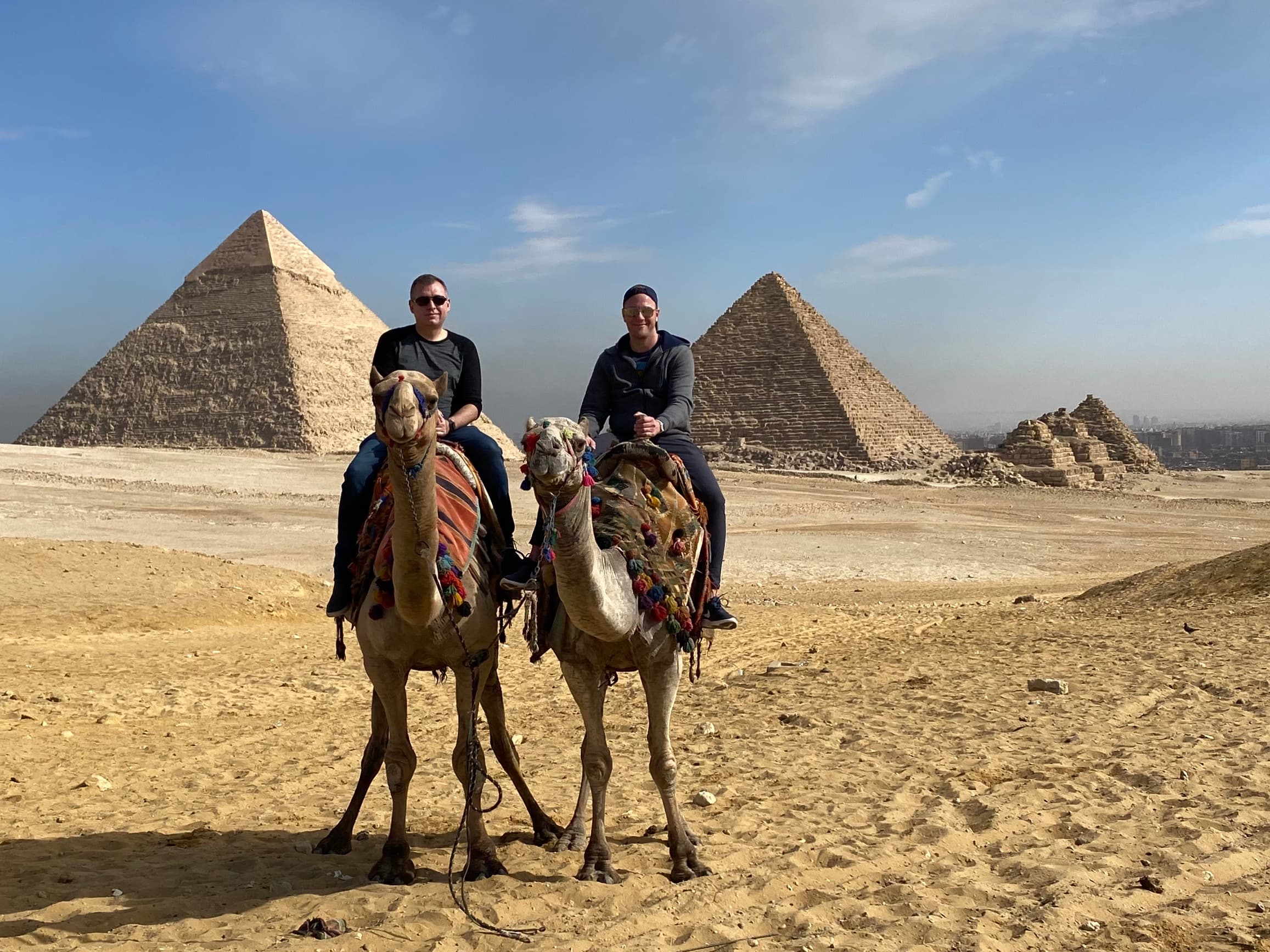 Anthony and a friend riding a camel in front of the Pyramids of Giza.