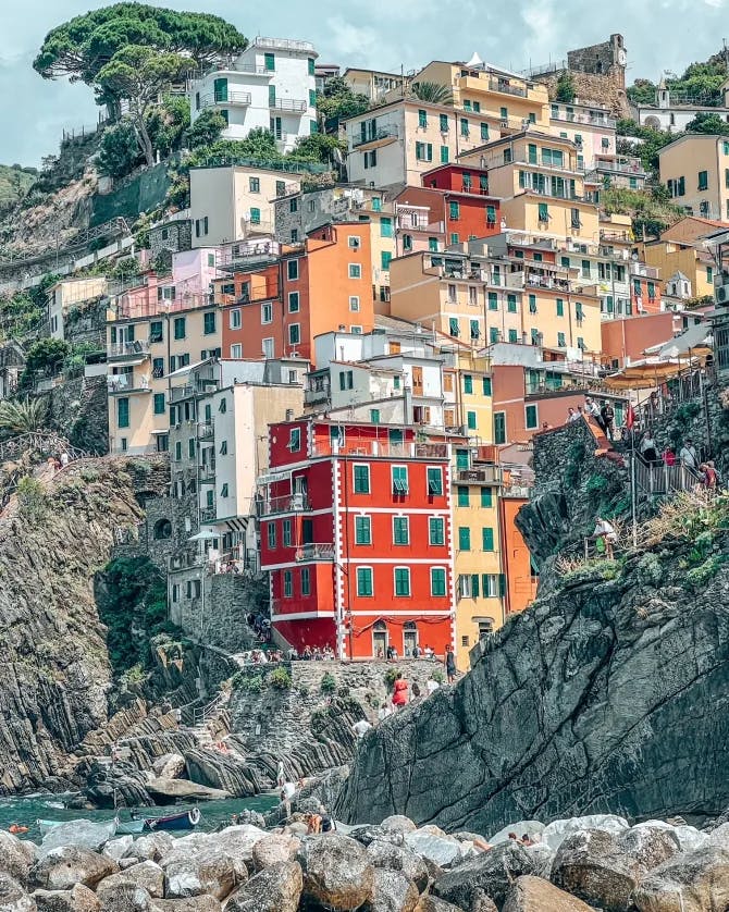 A view of colorful buildings tucked into a coastal mountainside surrounded by sea water in Northern Italy