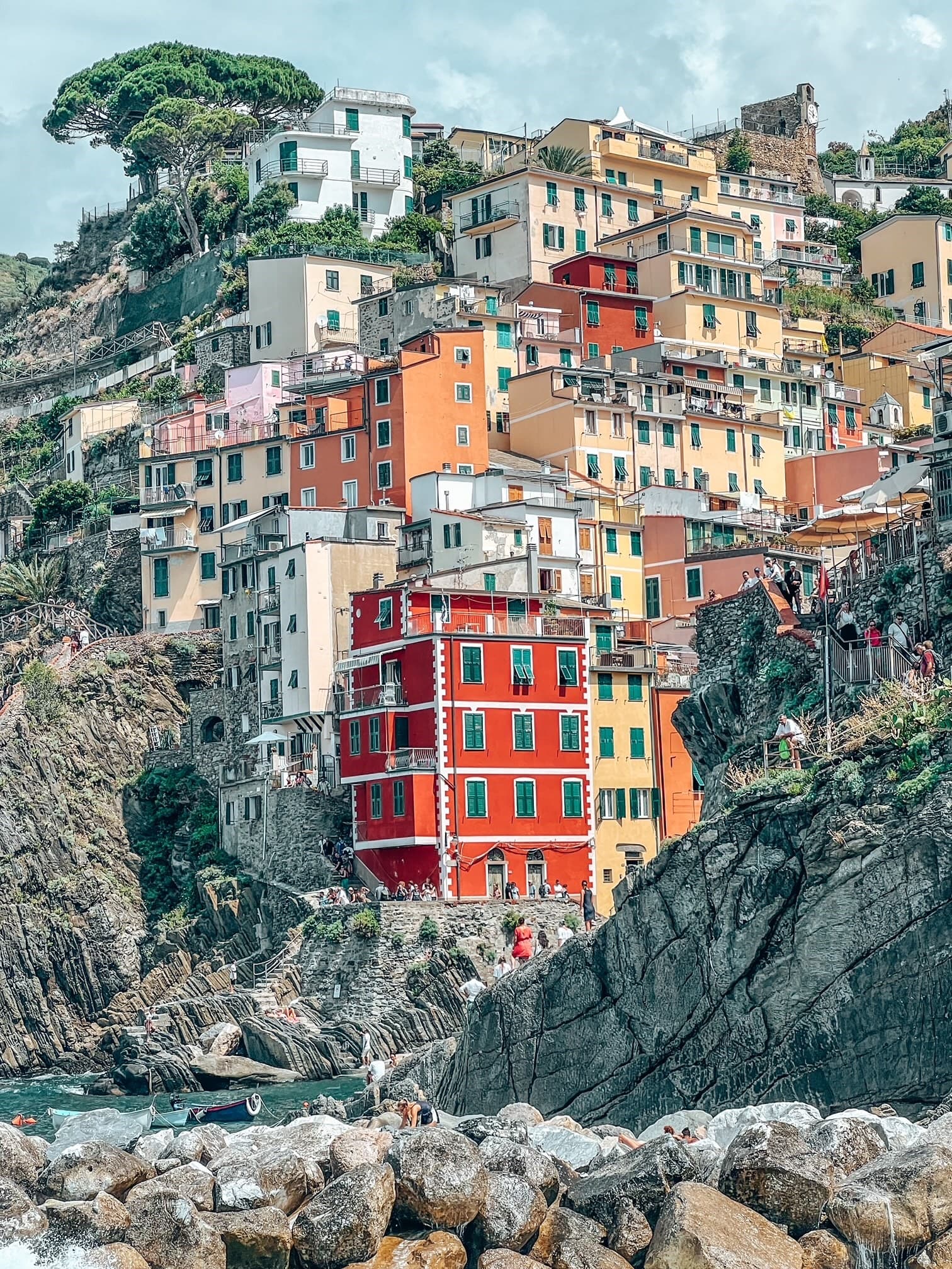 A view of colorful buildings tucked into a coastal mountainside surrounded by sea water in Northern Italy