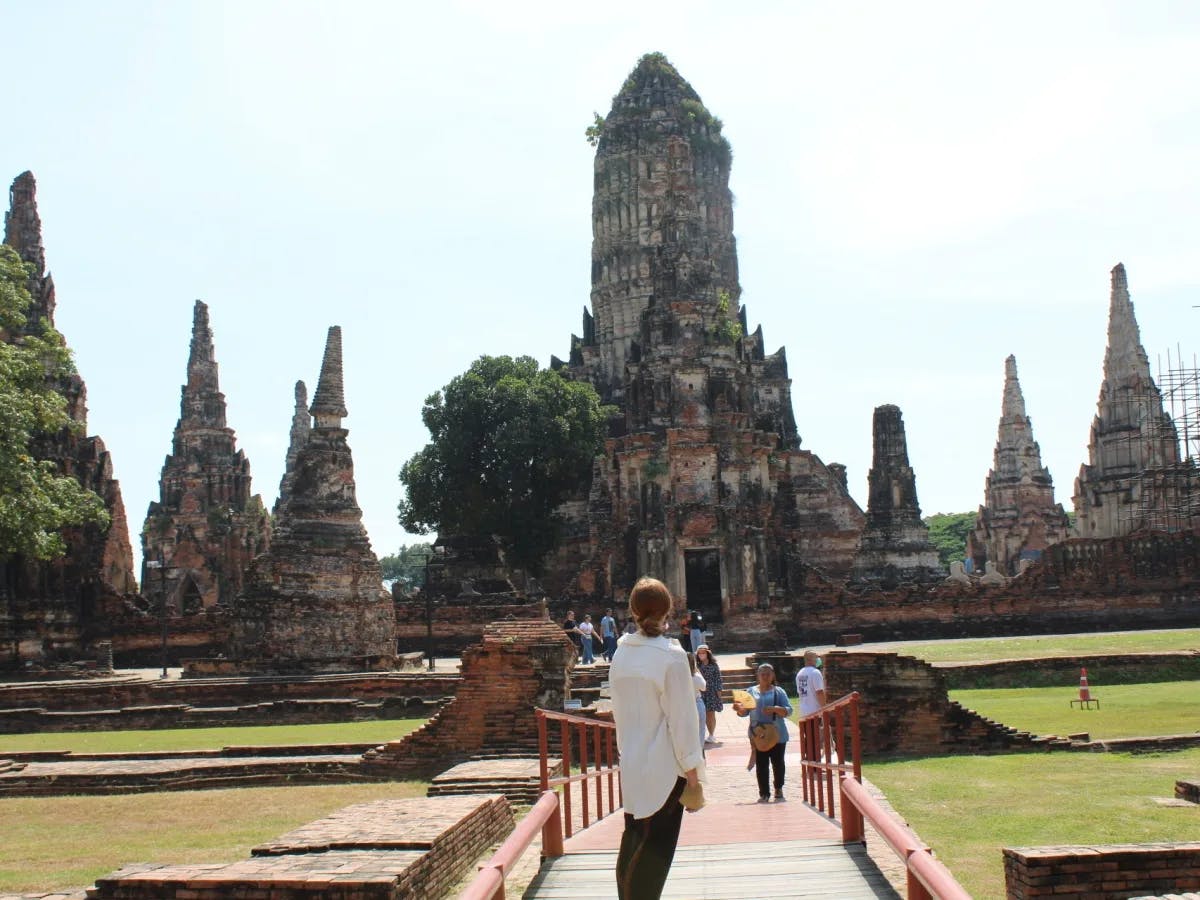 A picture of people standing before a temple called Wat Phra Si Sanphet during the daytime.