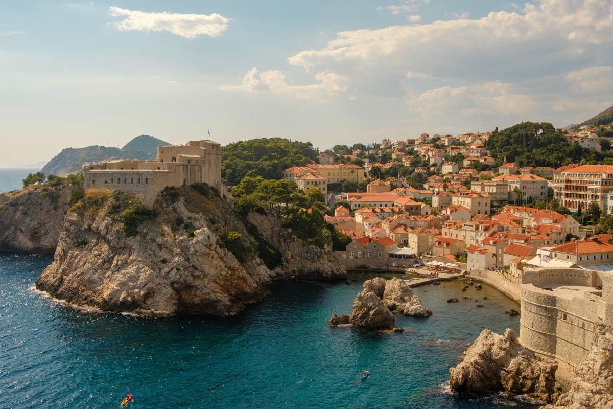Croatia coast flanked by a cliff dotted with red and white clay and stone buildings 