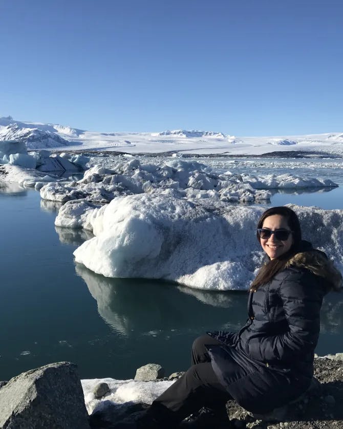 advisor sitting on a rock in front of a body of water with ice formations