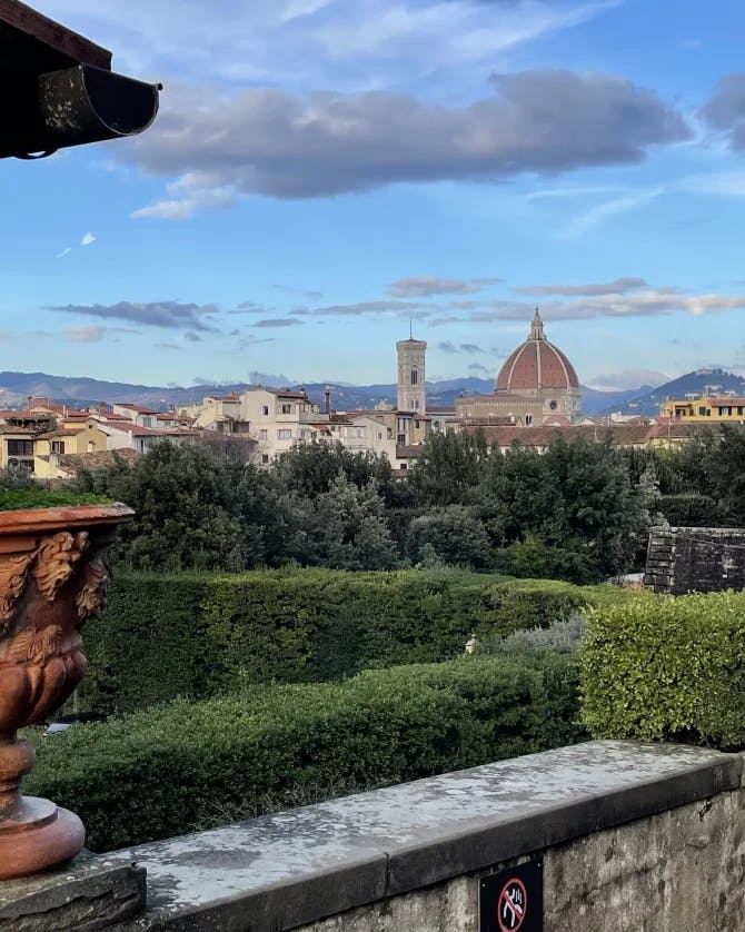 A stone wall with a pot and hedges overlooking Florence, Italy