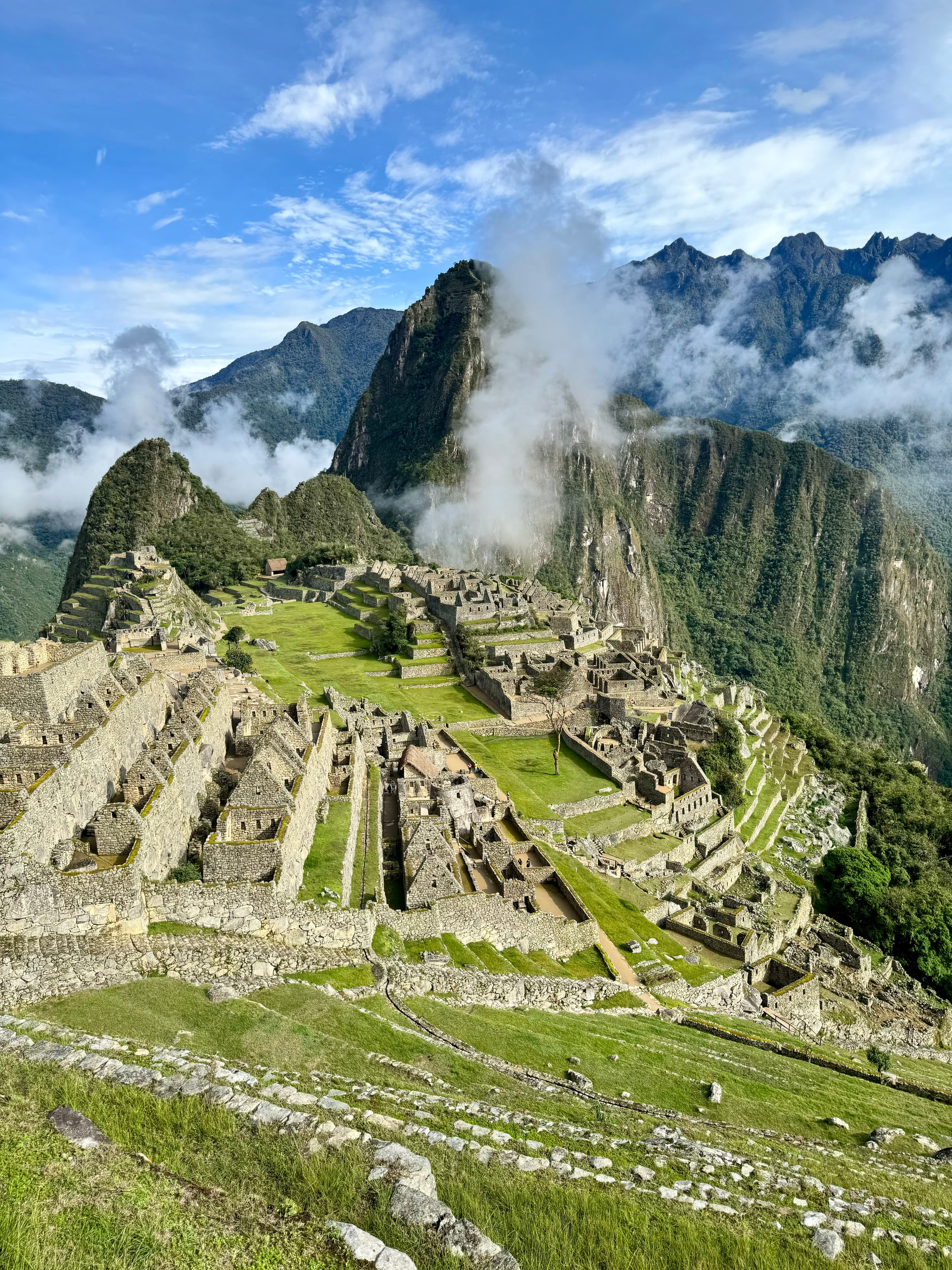 Picture of Historic Sanctuary of Machu Picchu with clouds against the peak in front of a blue sky