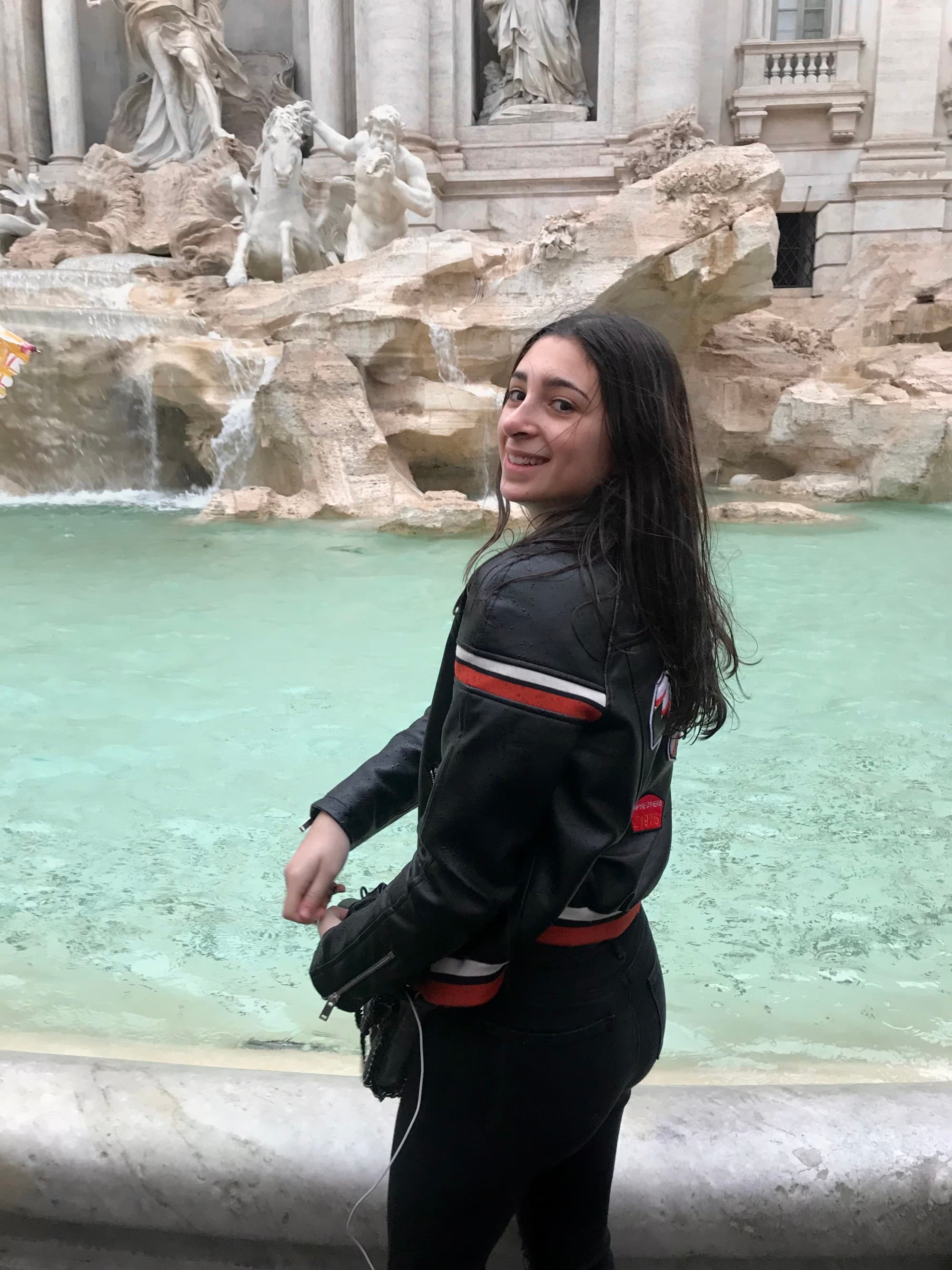 Travel Advisor in black track suit in front of fountain.