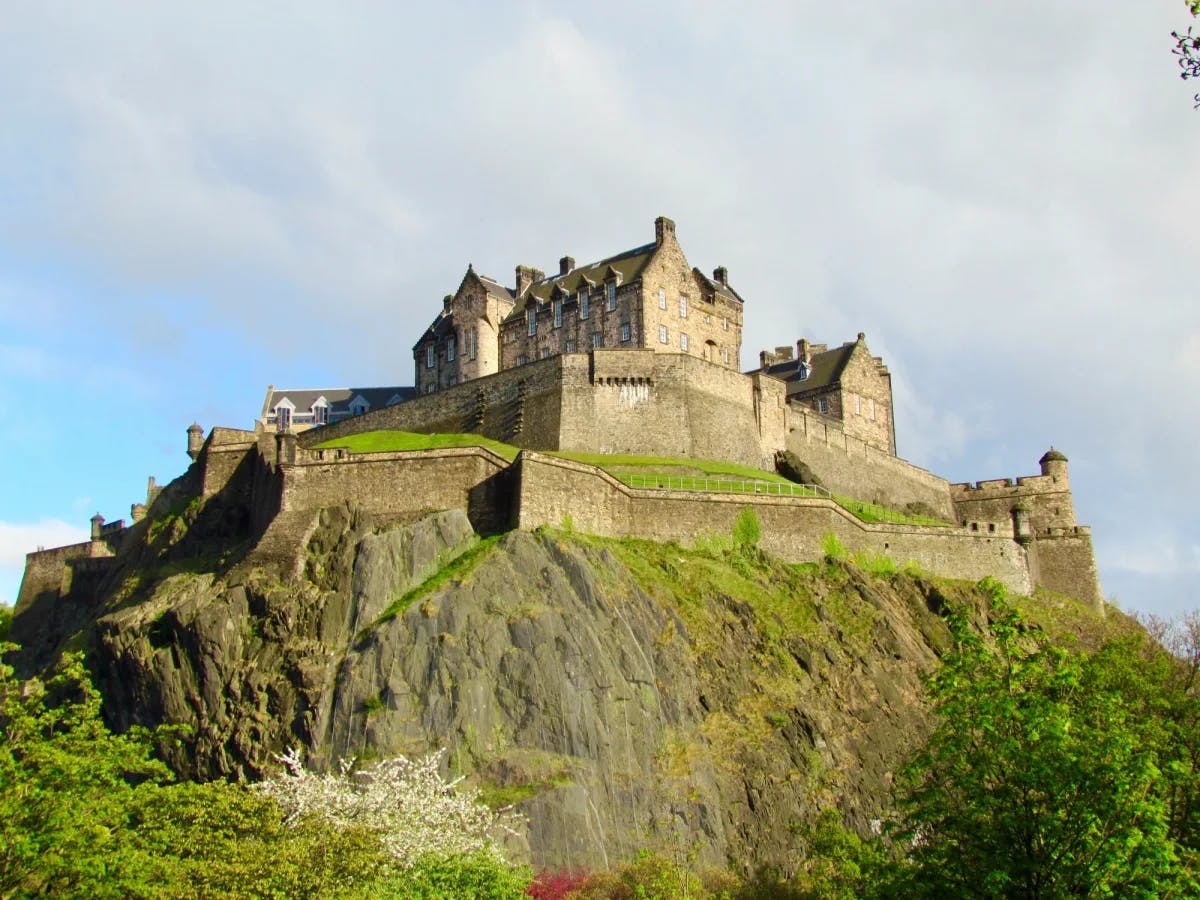 Edinburgh castle set atop a hill with walls and green foliage