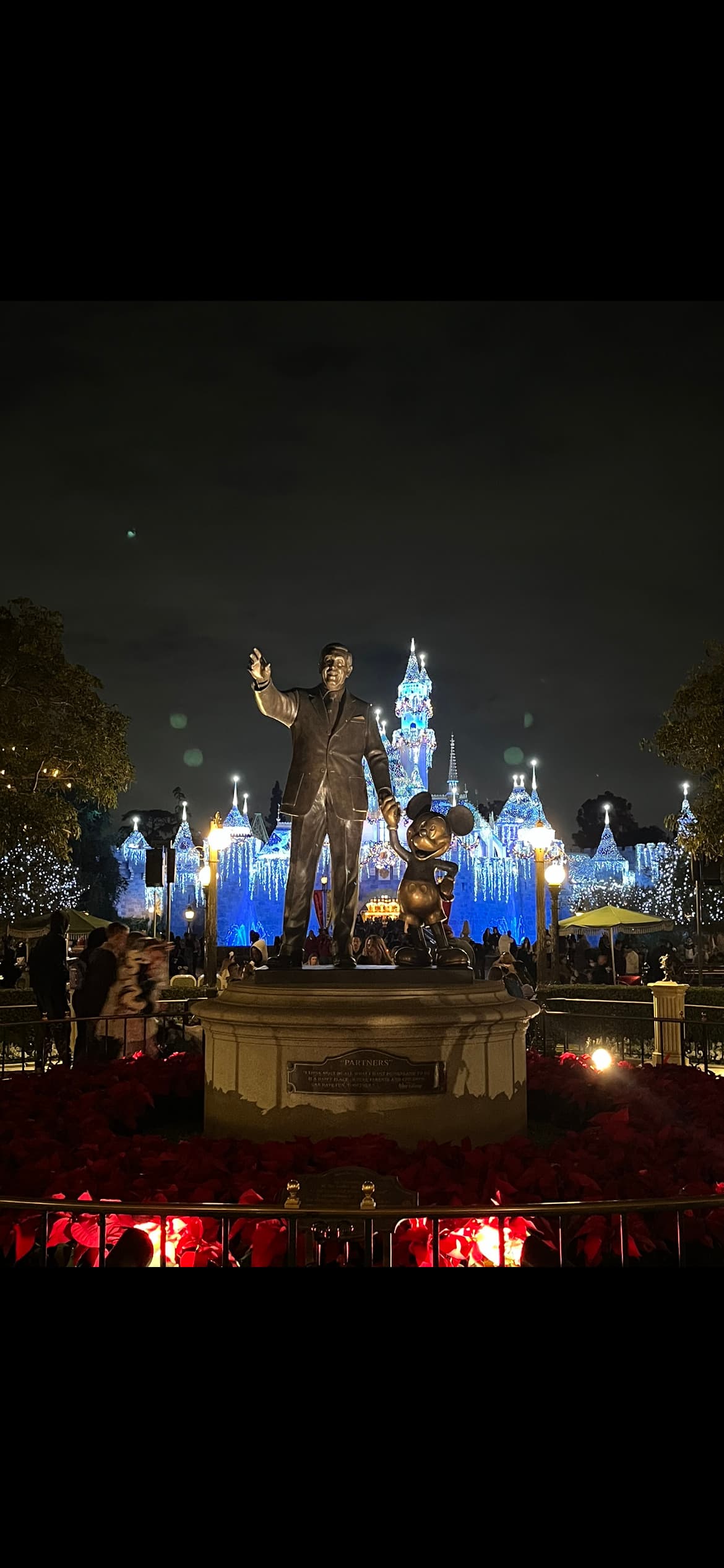 Picture of the Walt Disney statue at night in front of the lit up castle