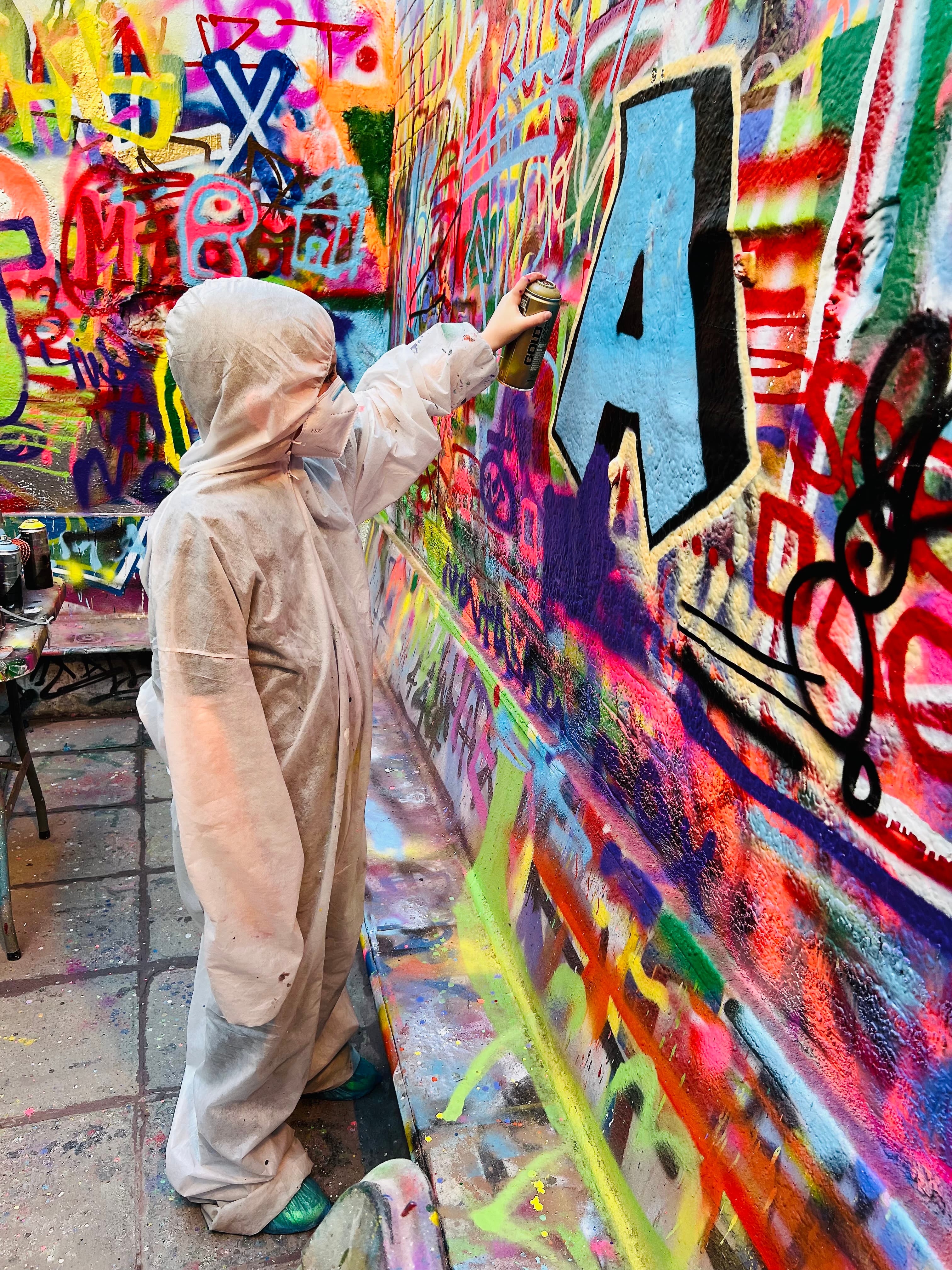 A child adding his own art to a graffiti wall.