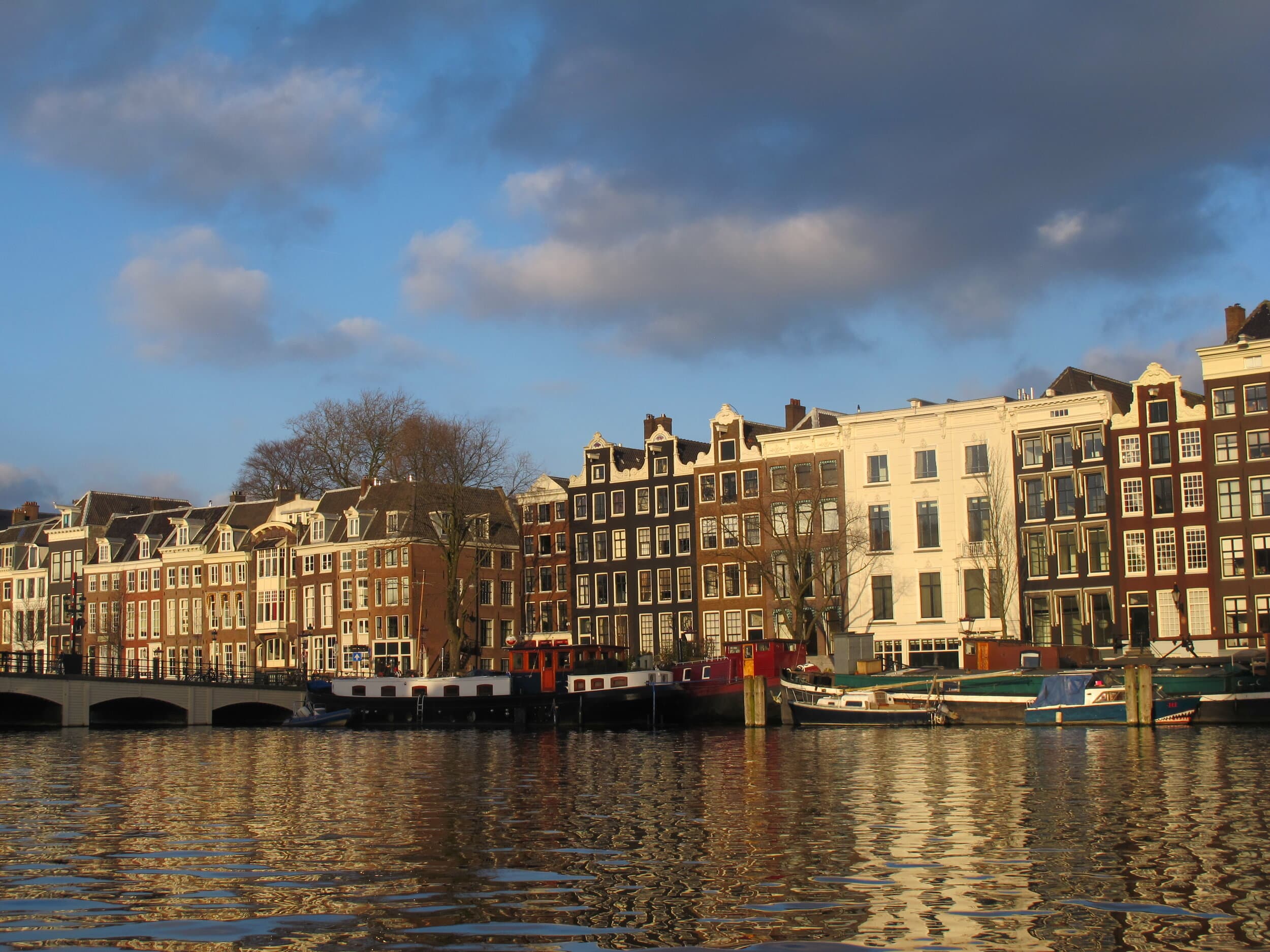 A view of the Amsterdam canal with boats docked and a line of buildings