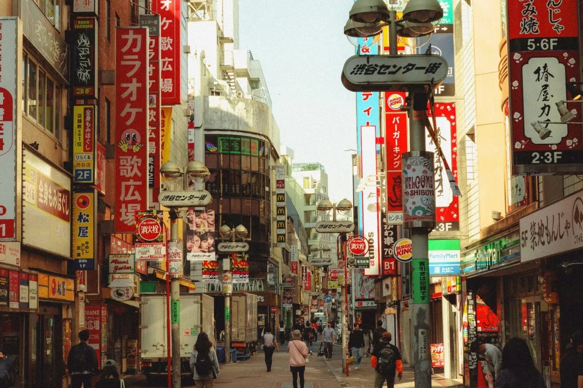 Hundreds of bright signs line a narrow, busy street in Shibuya, Tokyo