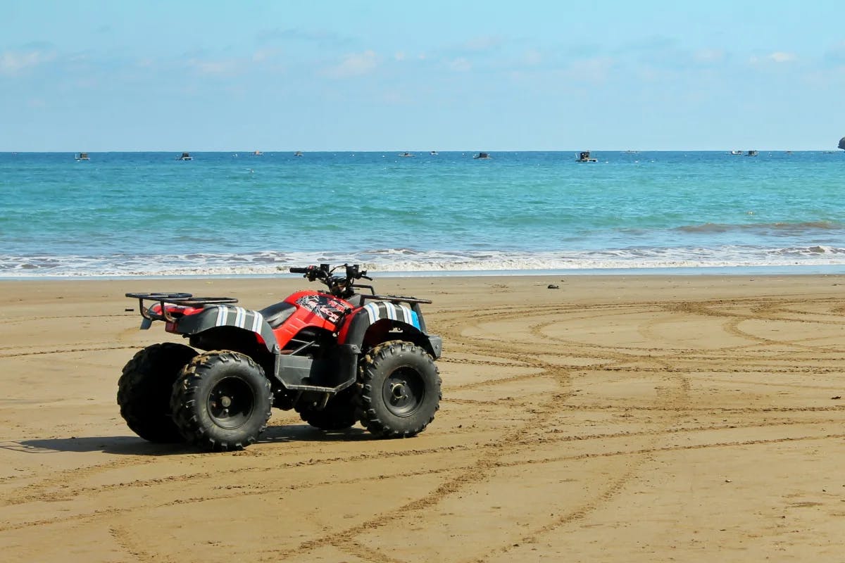 A picture of a quad bike standing near the seashore during the daytime.