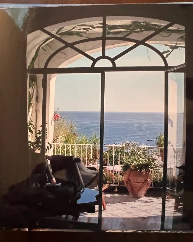 A piano in front of a large window with a terrace and sea view