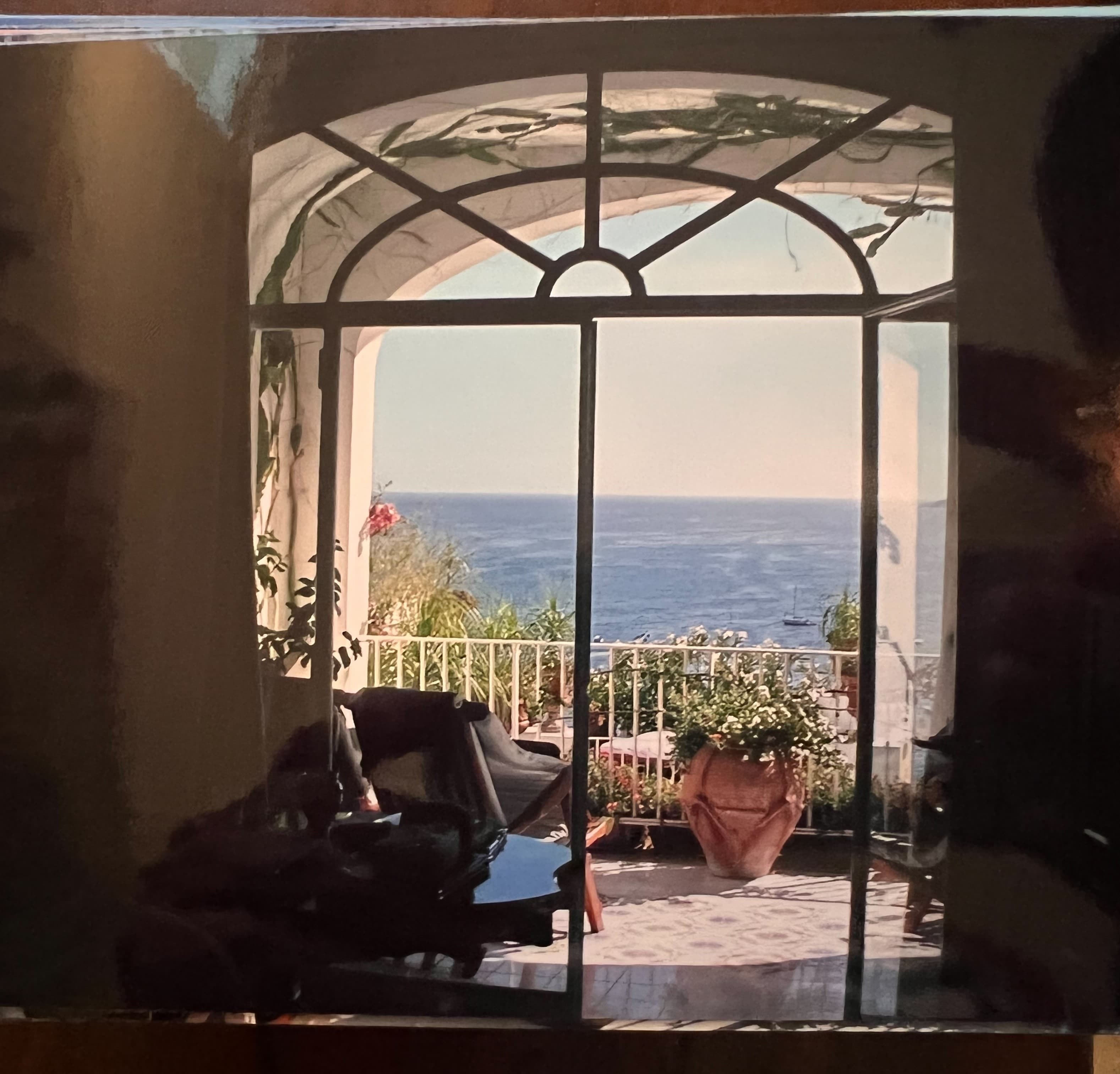 A piano in front of a large window with a terrace and sea view