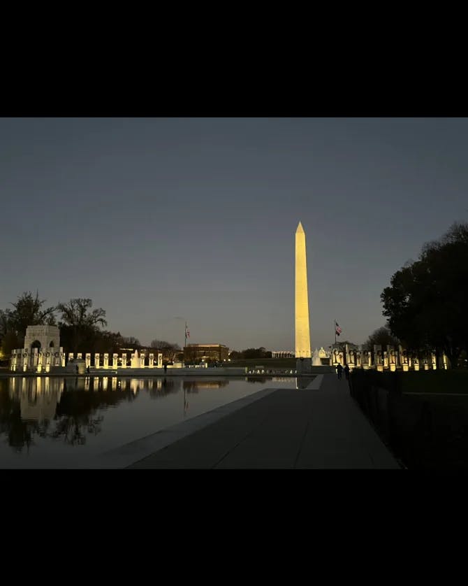 The Washington Monument lit up at nighttime over water