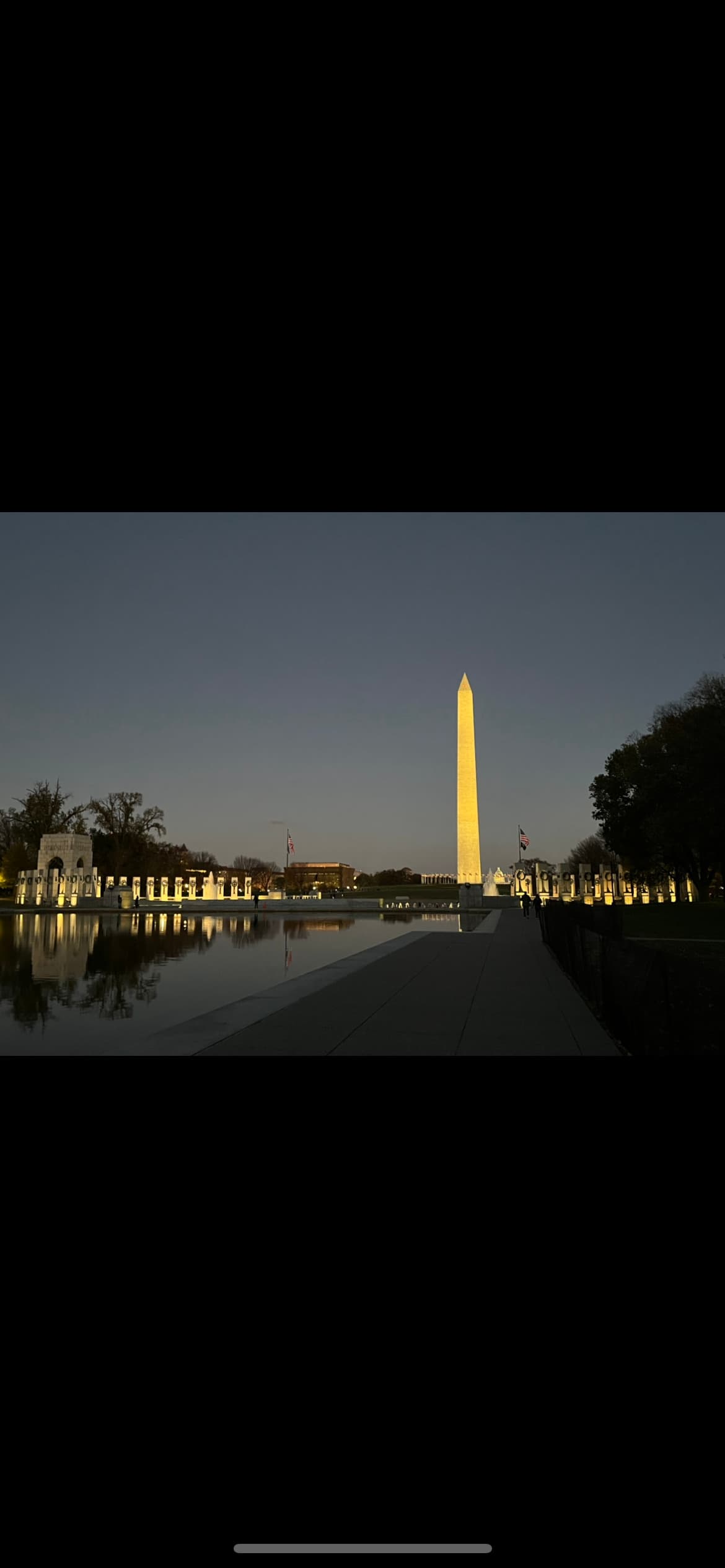 The Washington Monument lit up at nighttime over water