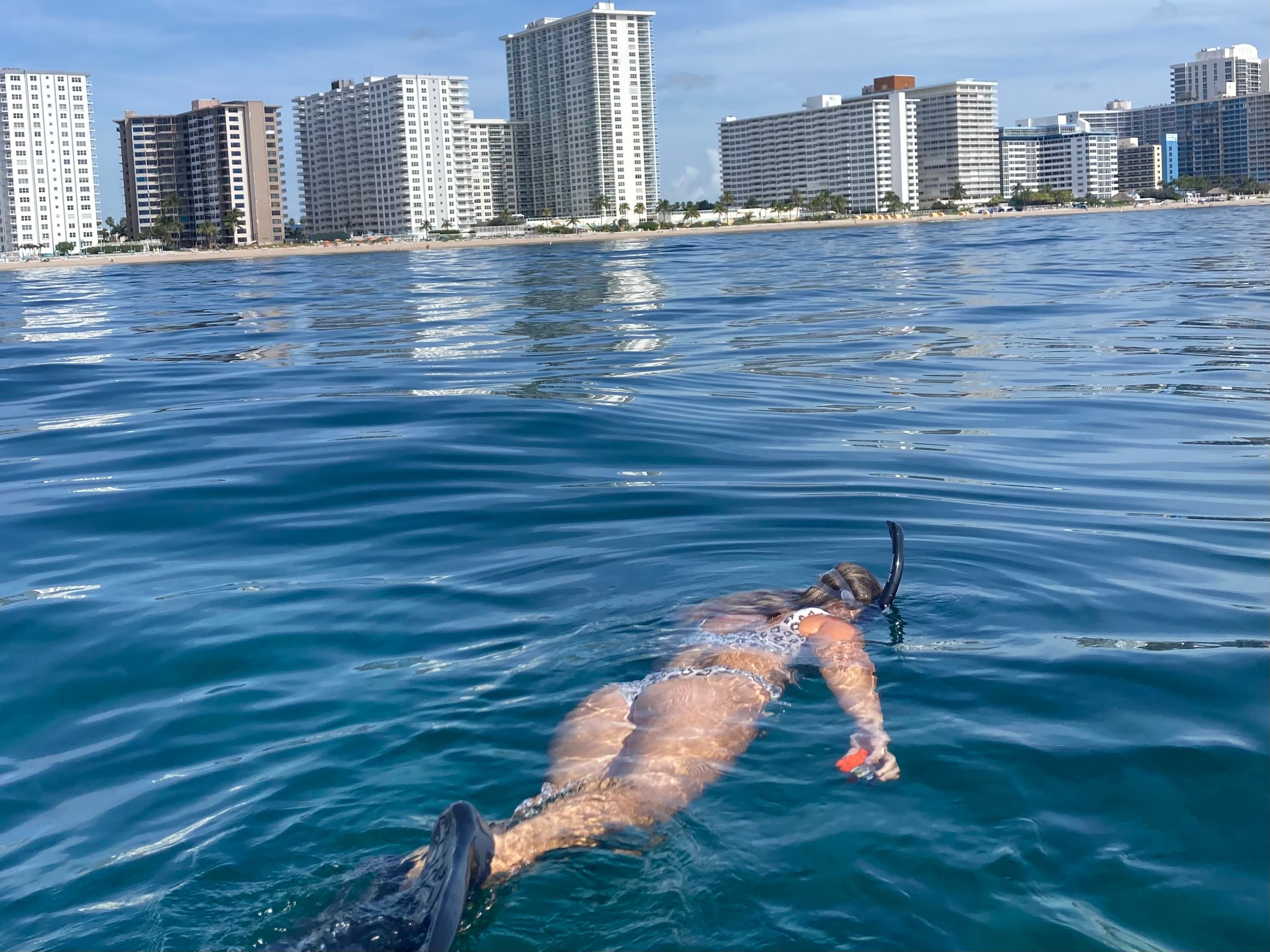 snorkeling in the sea with a coastline in the distance with hotels and palm trees.