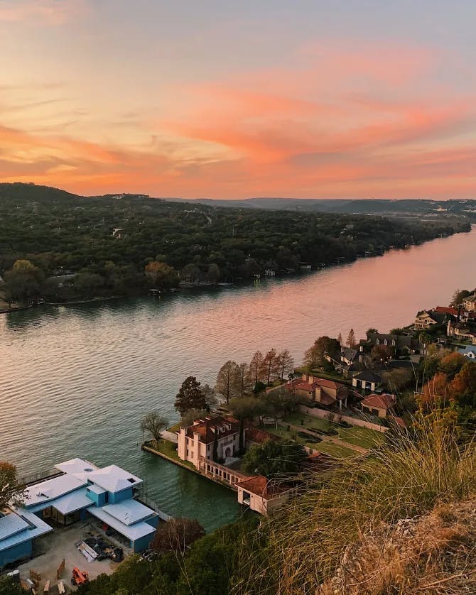 Picture of a beautiful view of Mount Bonnell near a river and orange hued sunset