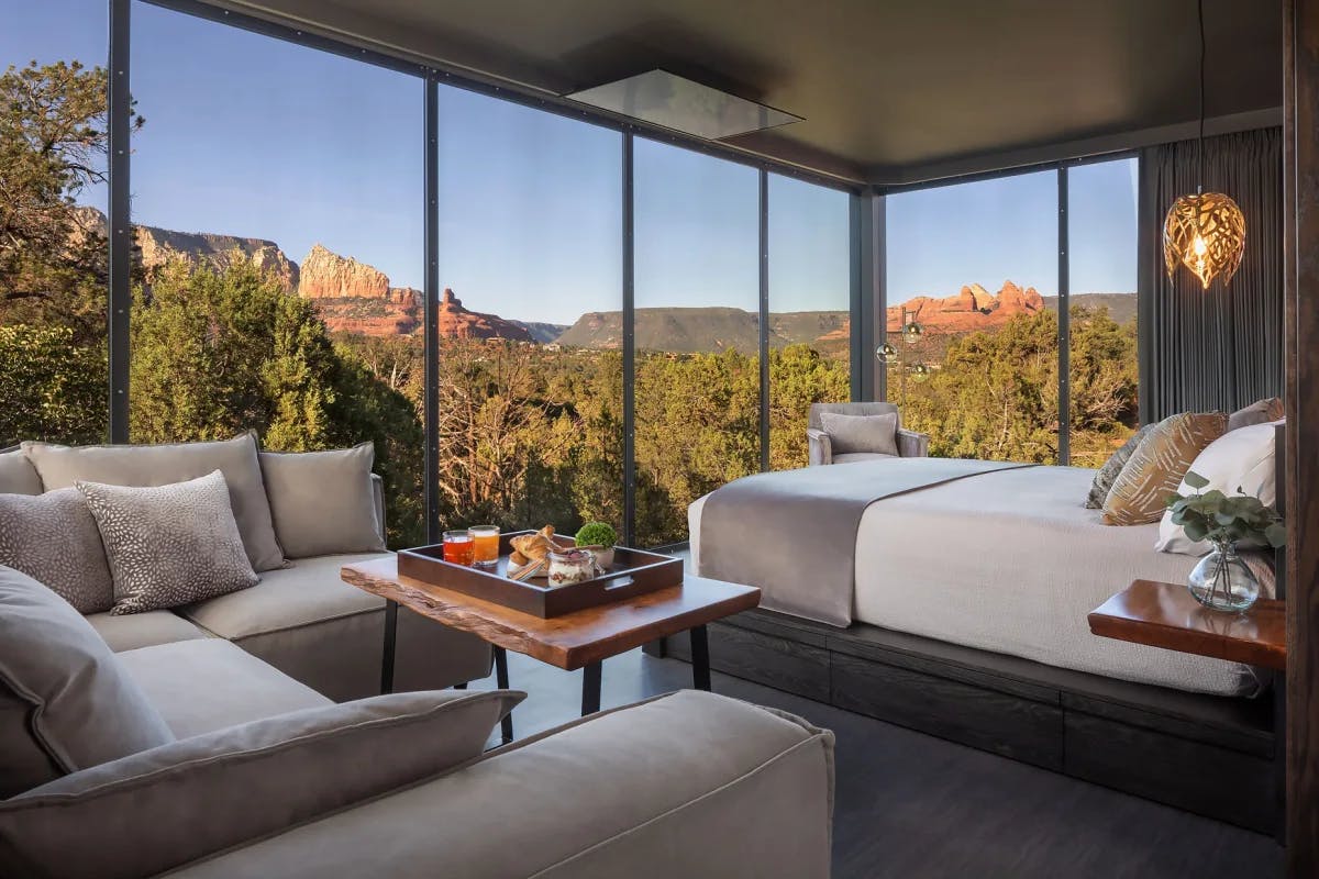 a bedroom with floor-to-ceiling windows overlooking a red-rock desert canyon