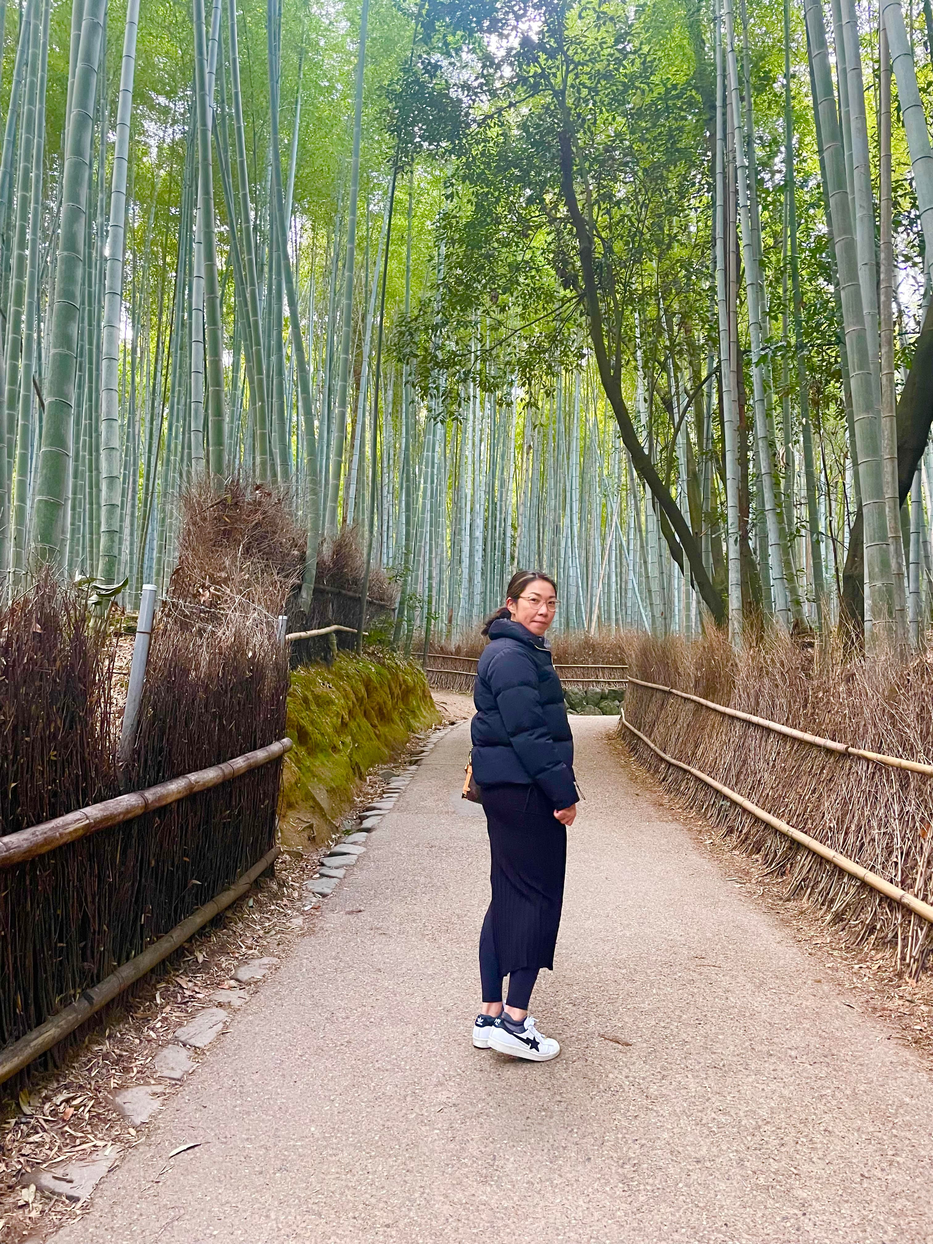 Kimberly posing on a dirt path surrounded by bamboo trees and wild brush.