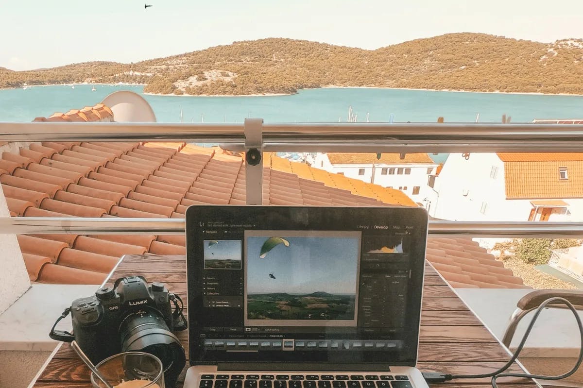 A person's work computer is set up on a rooftop somewhere in Croatia, with a gorgeous view of a harbor and historic homes 