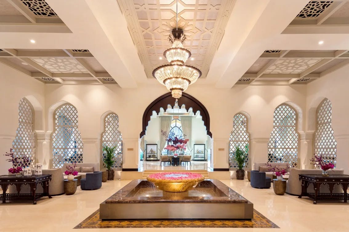 ornate lobby with a central fountain filled with water and pink flowers