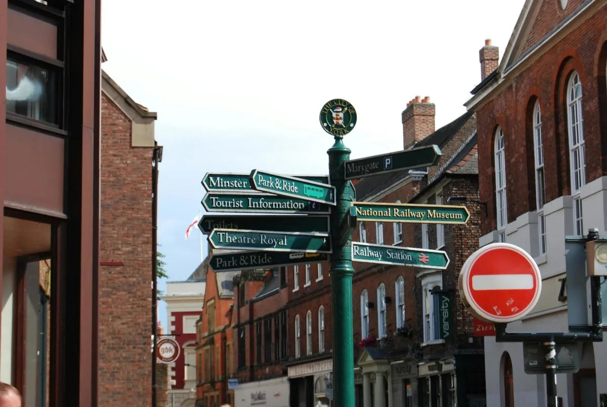 A signpost in historic York pointing in a dozen different directions, with one way prominently displaying a stop sign