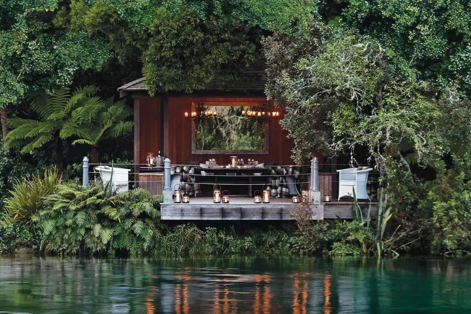 a wooden lakeside hut surrounded by greenery