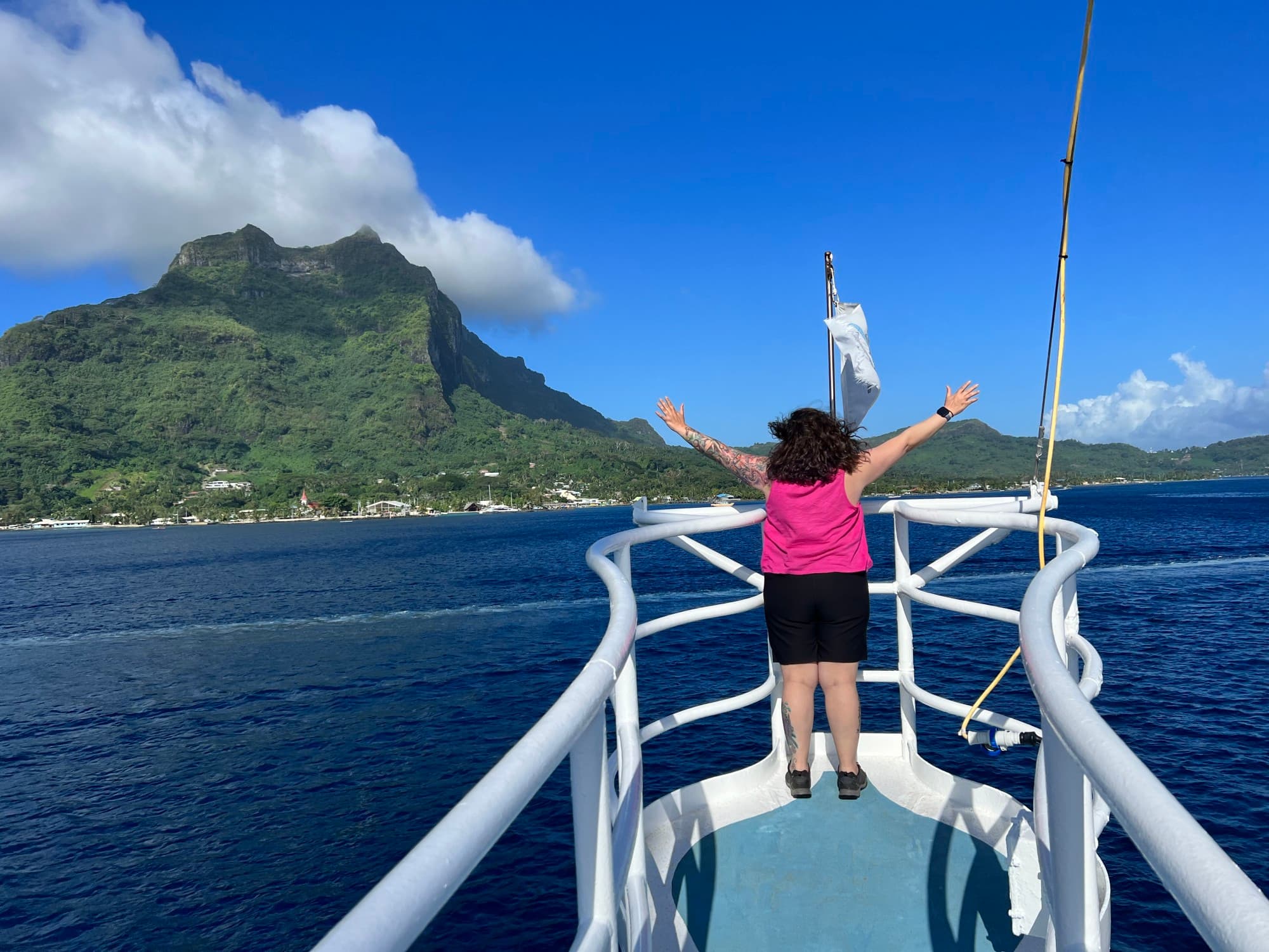 A woman in a pink top in a boat on a water body.