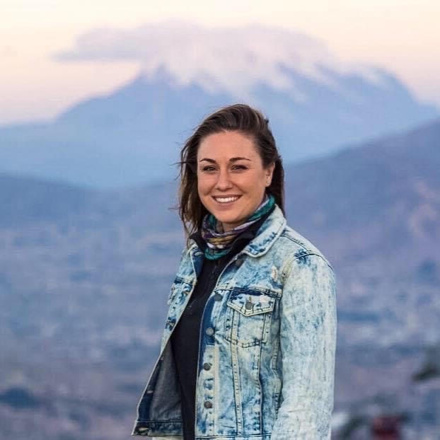 Travel advisor Lisa Hufnell in a jean jacket smiling in front of a snowy mountain peak