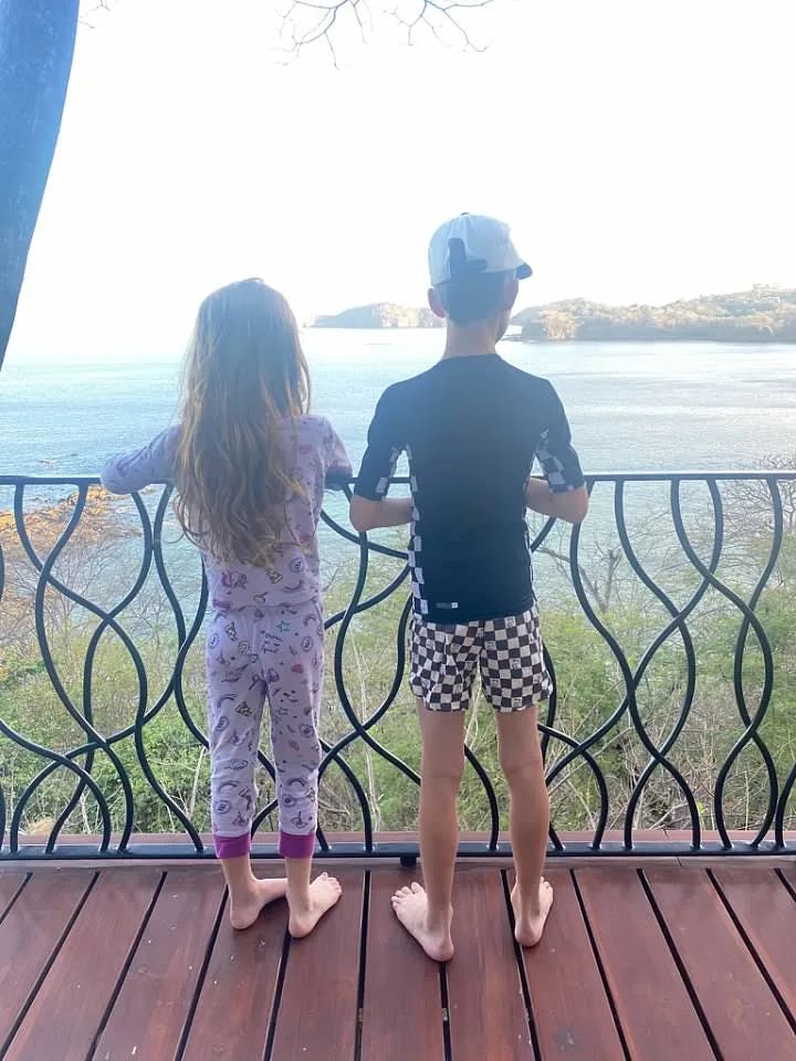 Lauren's children standing on a balcony overlooking the water.