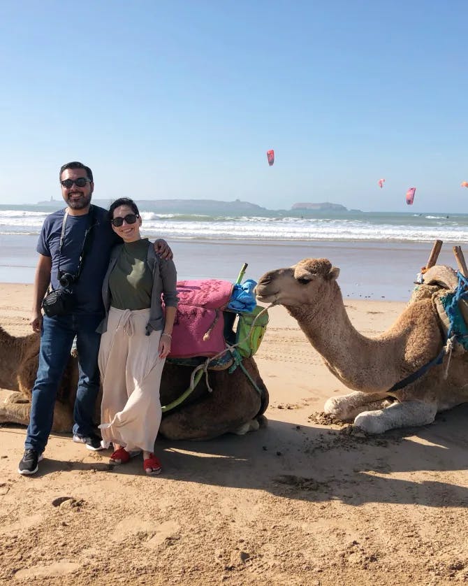Couple posing with two camels on the beach