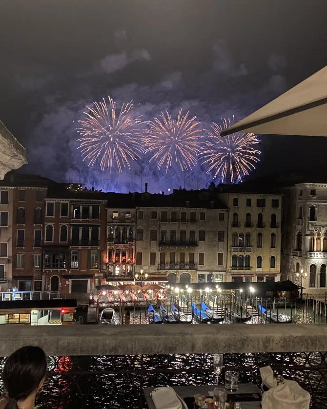 Picture of fireworks at night over buildings at the Grand Canal with a crowd of people watching